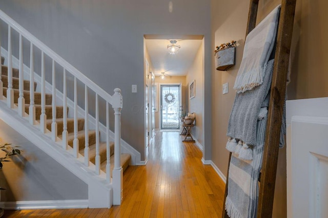 foyer featuring baseboards, light wood-style floors, and stairs