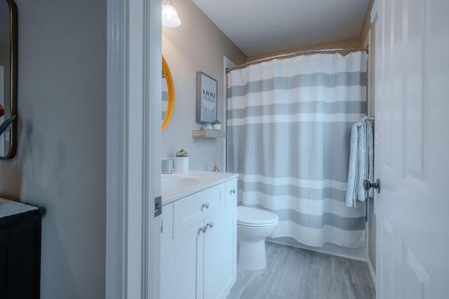 bathroom with toilet, vanity, a shower with curtain, and wood finished floors