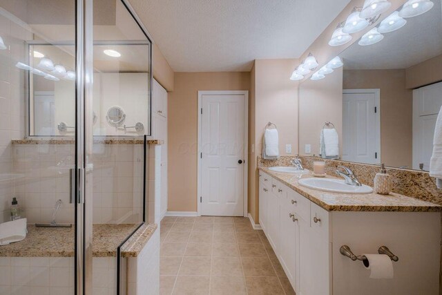 full bathroom with tile patterned flooring, double vanity, a stall shower, and a sink