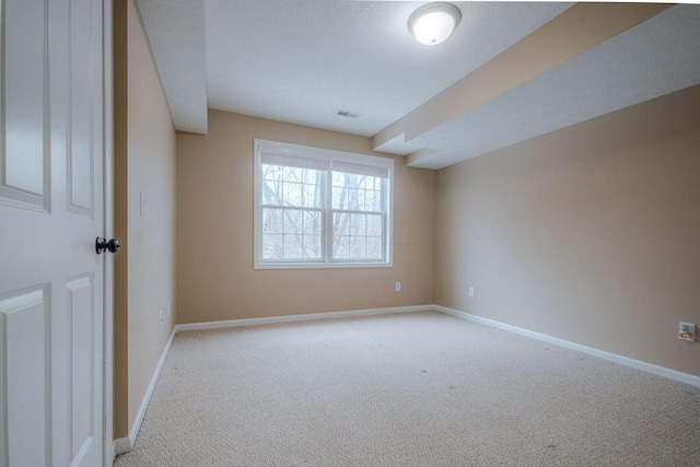 spare room with light carpet, visible vents, and baseboards