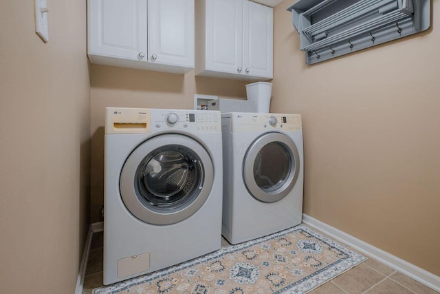 laundry area featuring baseboards, cabinet space, tile patterned flooring, and washer and clothes dryer