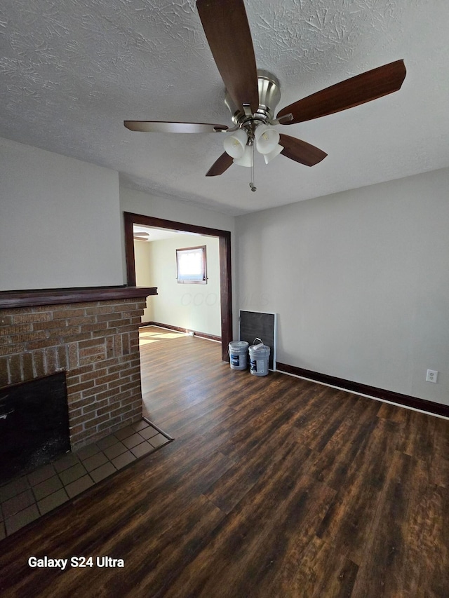 unfurnished living room with baseboards, a textured ceiling, wood finished floors, and a fireplace