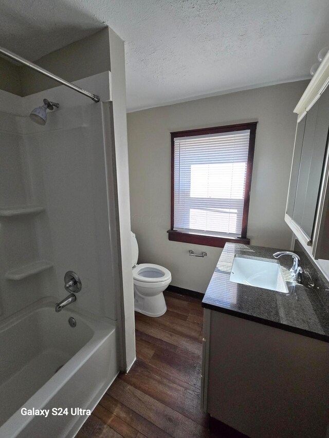 bathroom with toilet, a textured ceiling, wood finished floors, shower / bathing tub combination, and vanity