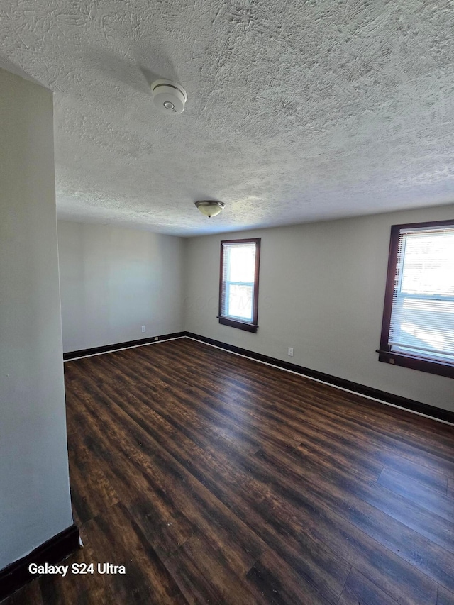 empty room featuring wood finished floors, baseboards, and a textured ceiling