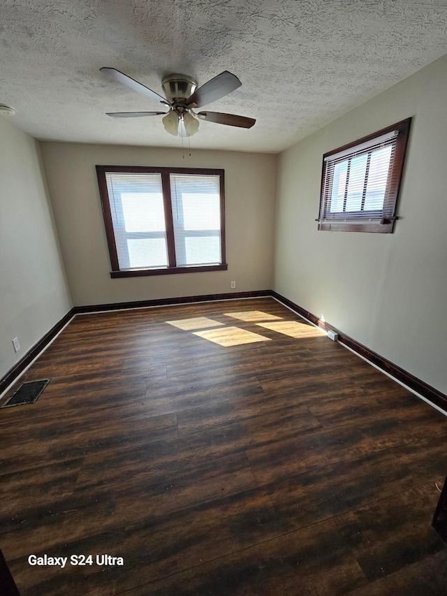 spare room featuring visible vents, baseboards, wood finished floors, a textured ceiling, and a ceiling fan