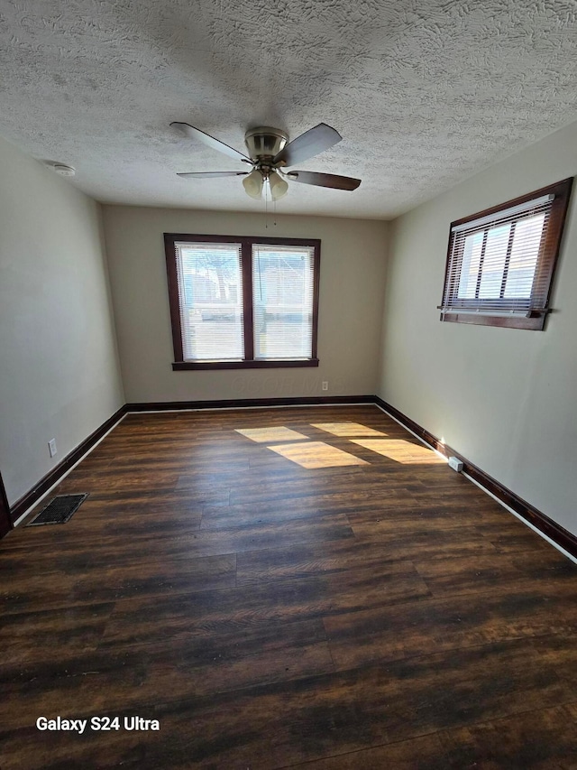 spare room featuring visible vents, a textured ceiling, baseboards, and wood finished floors