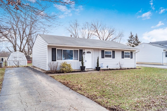 view of front of house with driveway, roof with shingles, an outdoor structure, and a front yard