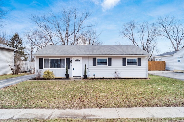 ranch-style home featuring driveway, a front lawn, and fence