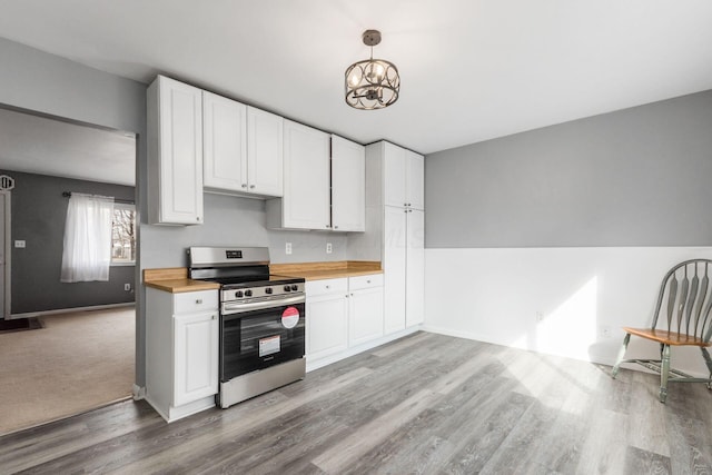 kitchen with light wood-style flooring, butcher block counters, white cabinets, stainless steel electric range, and an inviting chandelier