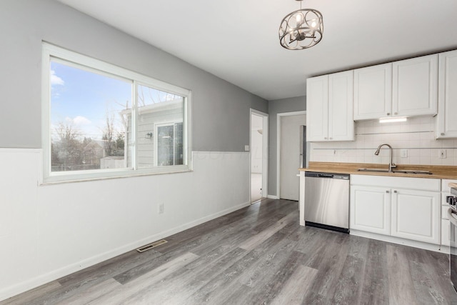 kitchen with light wood finished floors, butcher block counters, visible vents, stainless steel dishwasher, and a sink