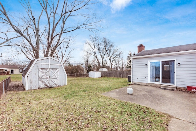 view of yard featuring a patio area, a shed, a fenced backyard, and an outbuilding