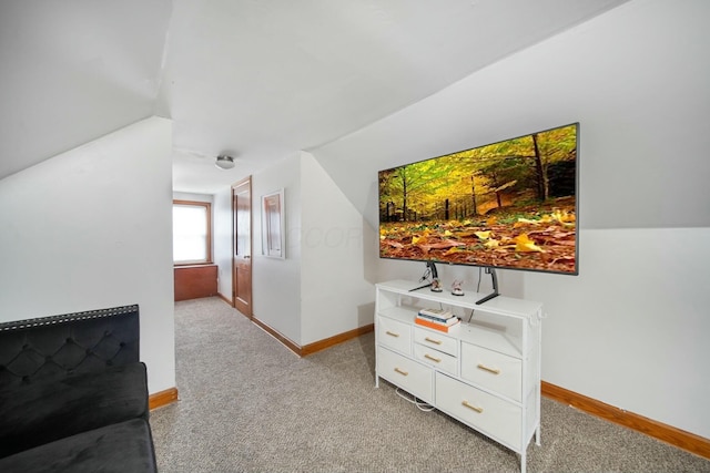 corridor with lofted ceiling, light colored carpet, and baseboards