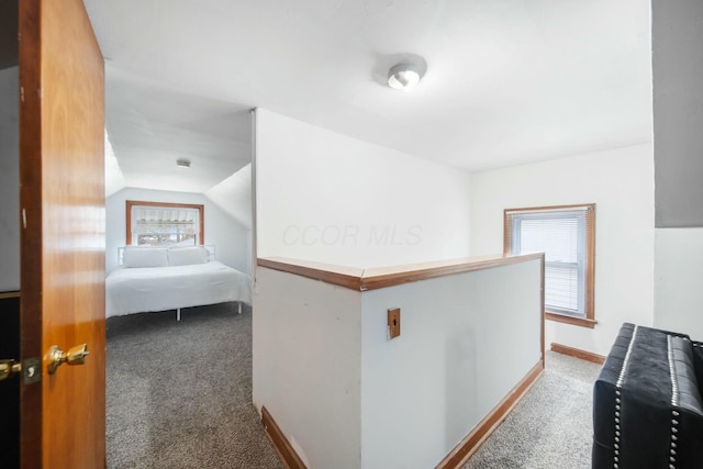 corridor with lofted ceiling, baseboards, carpet flooring, and an upstairs landing