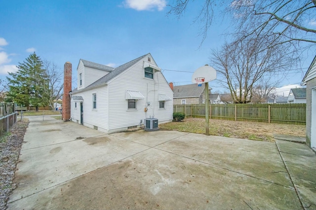 rear view of house featuring a fenced backyard, a chimney, cooling unit, and a patio