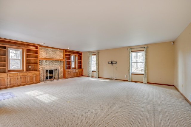 unfurnished living room featuring light carpet, a brick fireplace, built in features, and baseboards