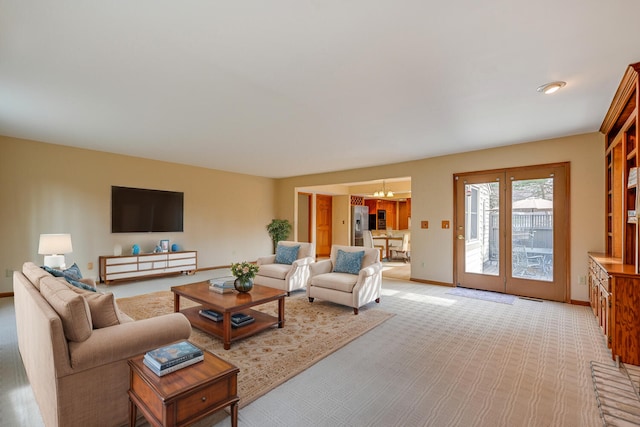 living area featuring light colored carpet, visible vents, baseboards, and an inviting chandelier