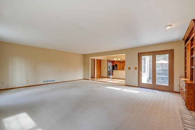 empty room with visible vents, light carpet, baseboards, and an inviting chandelier