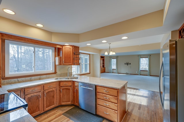 kitchen with a peninsula, brown cabinetry, stainless steel appliances, and a sink