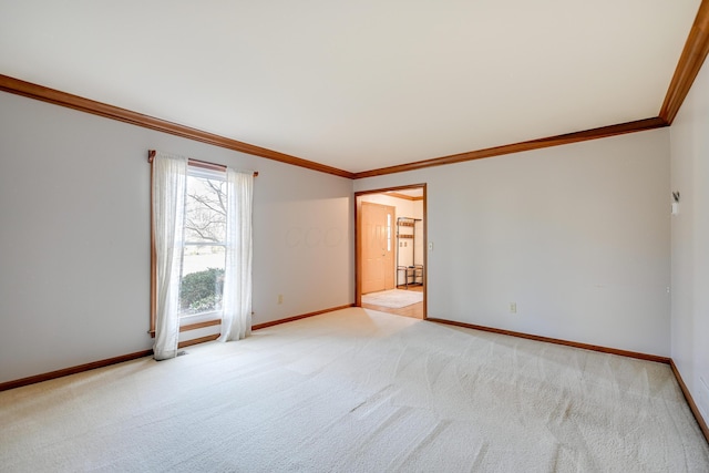 spare room featuring light colored carpet, crown molding, and baseboards