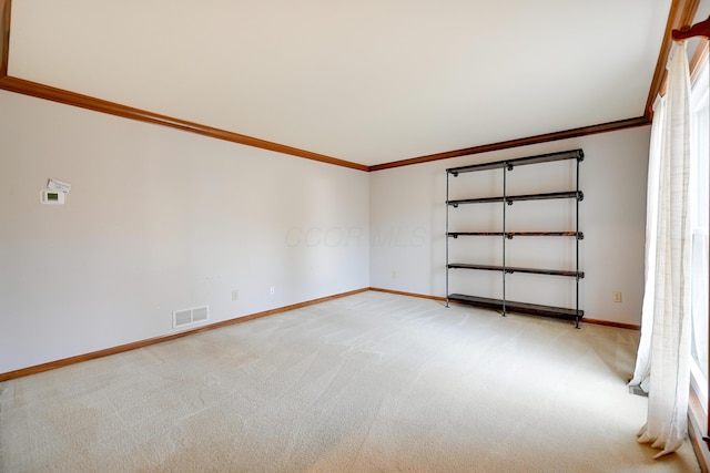 unfurnished room featuring light colored carpet, visible vents, crown molding, and baseboards