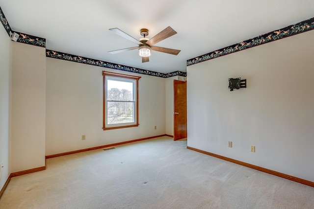 carpeted empty room featuring visible vents, a ceiling fan, and baseboards