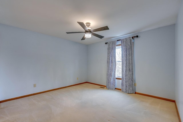 unfurnished room featuring ceiling fan, visible vents, baseboards, and light colored carpet