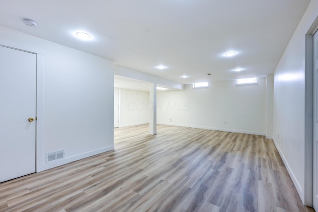 below grade area with wood finished floors, visible vents, and baseboards