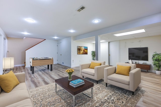 living area featuring visible vents, a drop ceiling, baseboards, and wood finished floors