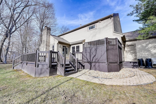 rear view of property featuring a chimney, a deck, and a yard