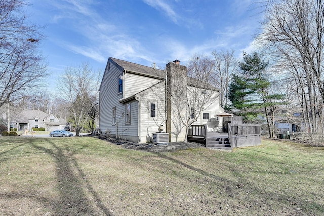 view of side of home featuring a deck, a chimney, cooling unit, and a lawn