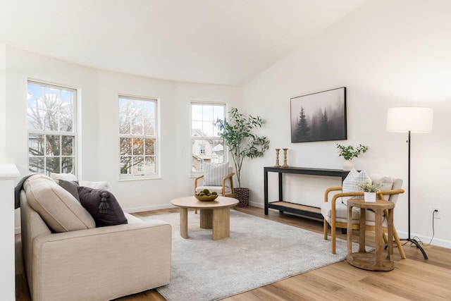 living area featuring baseboards, vaulted ceiling, and wood finished floors