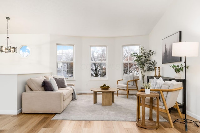 living room featuring a chandelier, light wood-style flooring, and baseboards