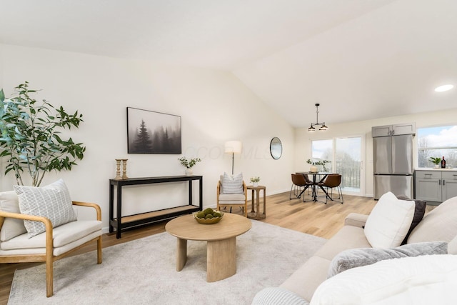 living room featuring light wood-style floors, lofted ceiling, plenty of natural light, and baseboards