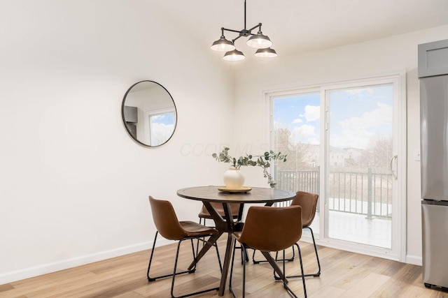 dining area with light wood-style flooring, baseboards, and an inviting chandelier