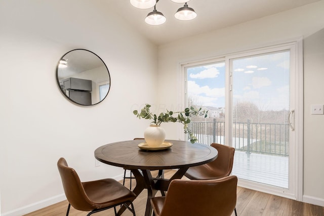 dining room with vaulted ceiling, light wood-style flooring, baseboards, and an inviting chandelier