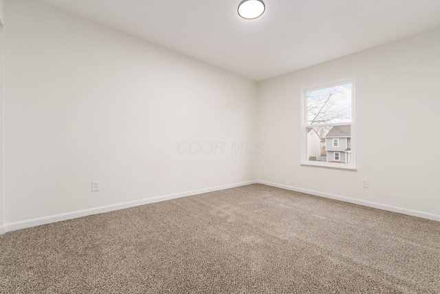 carpeted empty room featuring baseboards