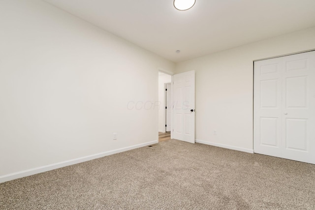 unfurnished bedroom featuring carpet floors, a closet, and baseboards