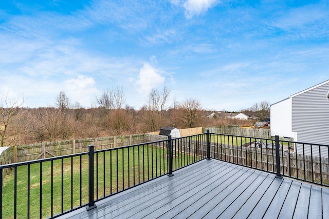 deck featuring an outbuilding, a storage unit, a lawn, and a fenced backyard