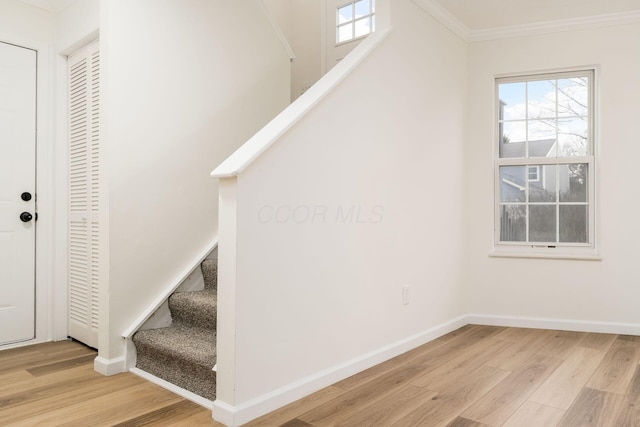 staircase featuring a wealth of natural light, crown molding, baseboards, and wood finished floors