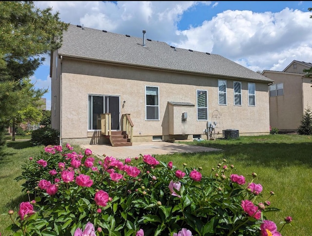 back of house with entry steps, a yard, a patio, and stucco siding