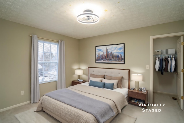 bedroom with carpet floors, baseboards, a walk in closet, and a textured ceiling