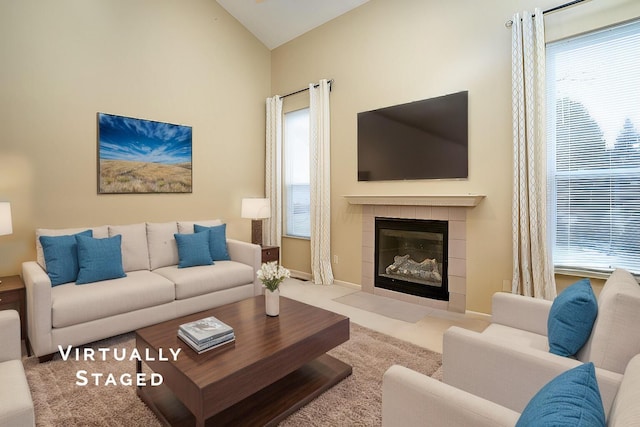 living area with vaulted ceiling, carpet floors, a tile fireplace, and baseboards