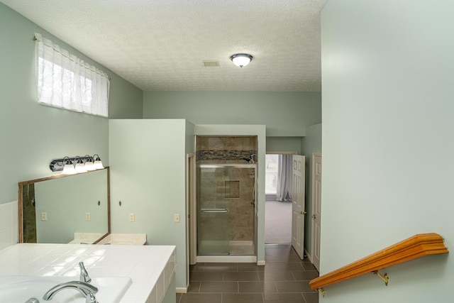 bathroom with a stall shower, tile patterned floors, a sink, a textured ceiling, and a bath