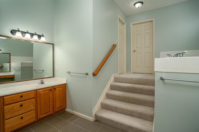 bathroom with baseboards, a textured ceiling, and vanity