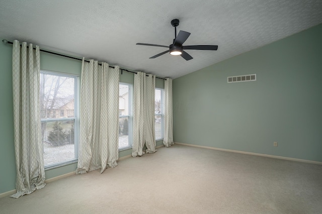 carpeted empty room with a ceiling fan, lofted ceiling, visible vents, and a textured ceiling