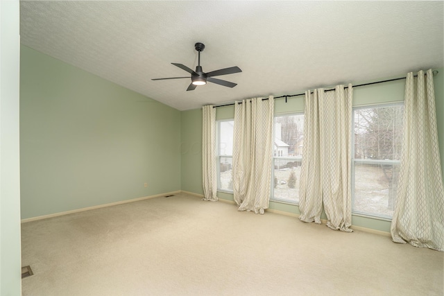 spare room featuring carpet floors, vaulted ceiling, ceiling fan, a textured ceiling, and baseboards