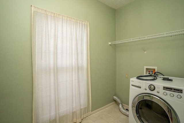 clothes washing area featuring washer / clothes dryer, a textured ceiling, baseboards, and laundry area