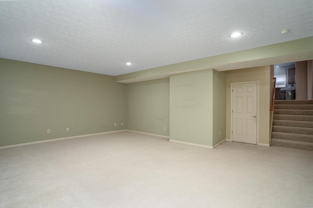 finished basement with a textured ceiling, recessed lighting, light colored carpet, baseboards, and stairway