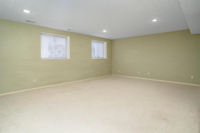 empty room featuring a textured ceiling, recessed lighting, baseboards, and light colored carpet