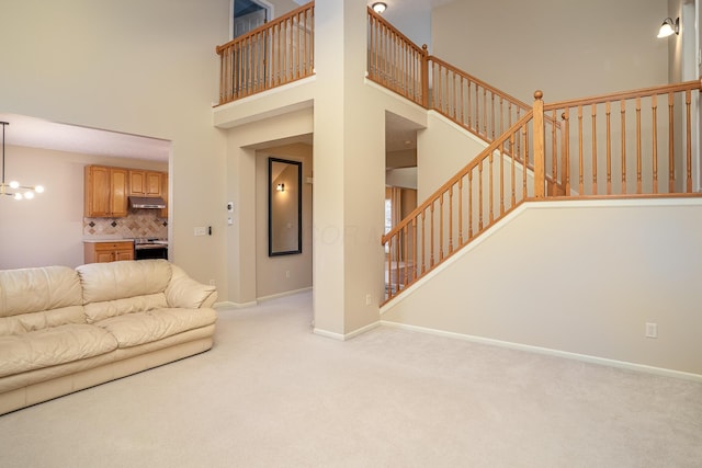 unfurnished living room featuring a towering ceiling, carpet, stairway, and baseboards